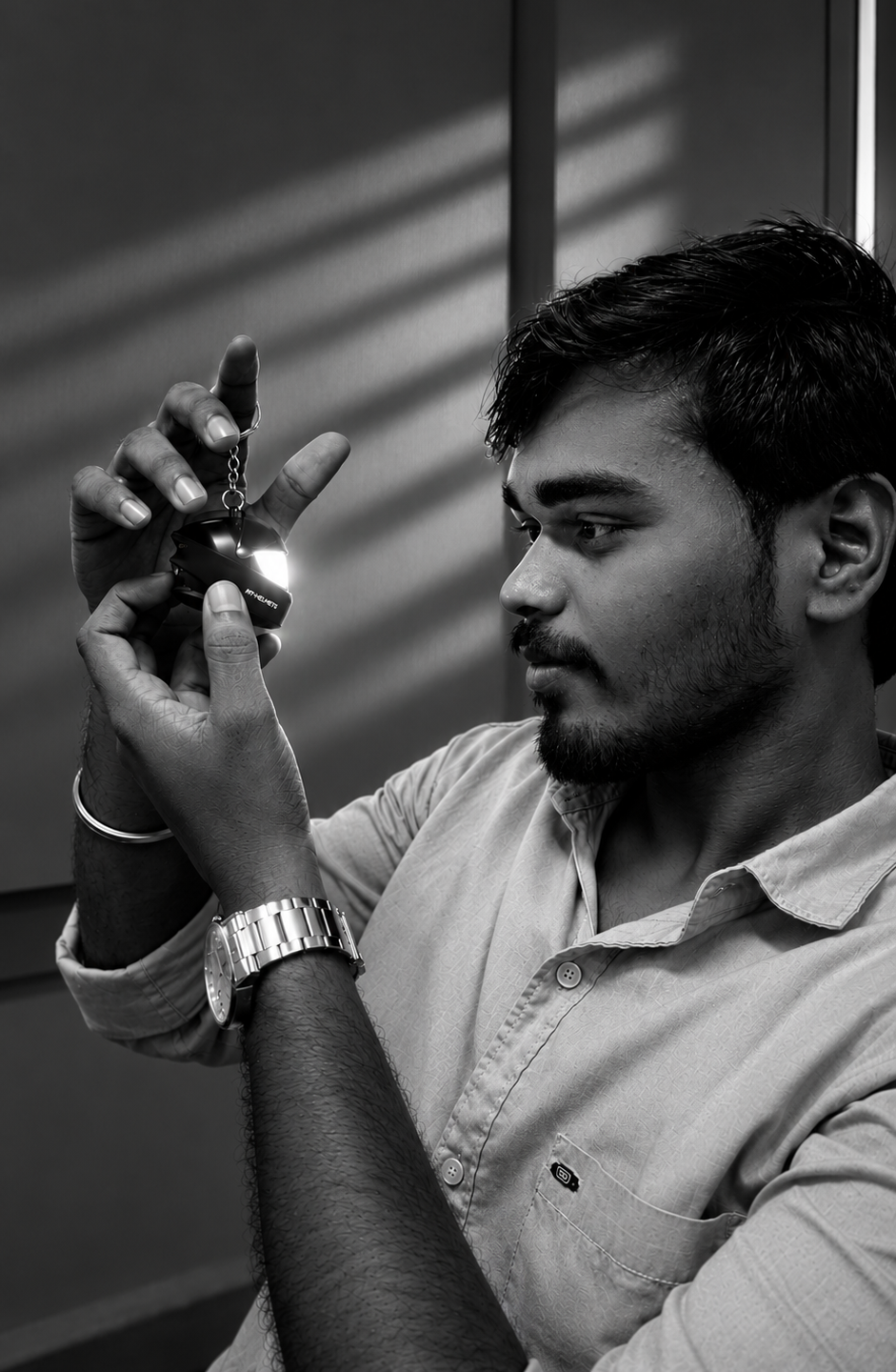 Yogesh examining an illuminated miniature helmet with focused curiosity